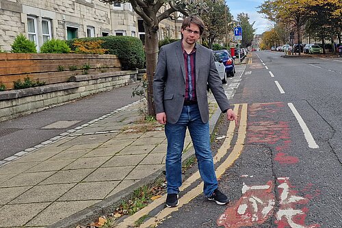 A man pointing at a worn away bicycle lane on McDonald Road