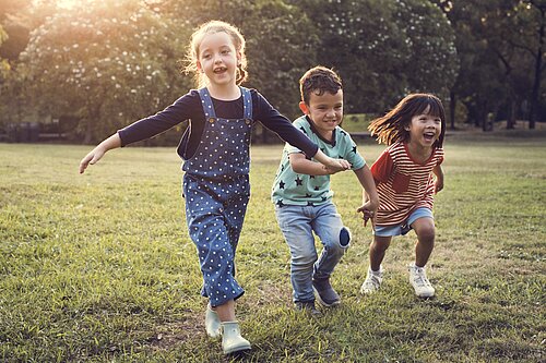 Three children playing outside on the grass.