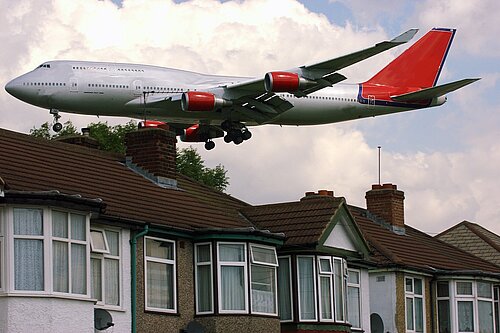 A plane flying close to houses.