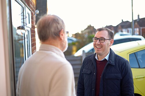 Tom Gordon stood on a doorstep talking to a local resident