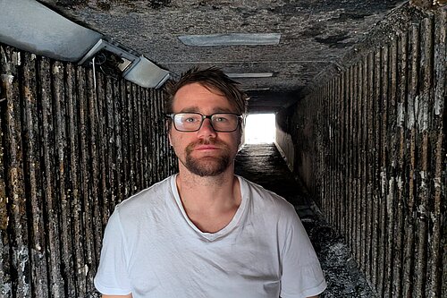 Stephen O'Brien standing in a badly fire-damaged subway