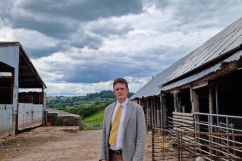 David Chadwick MP standing in front of farm stabbles outside Brecon